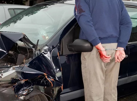 Man handcuffed near damaged car, in need of a Texas dram shop attorney