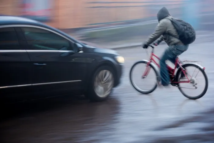 Car speeding about to hit pedestrian on bicycle causing an accident
